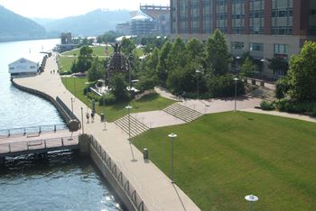 A park with a grassy area, a walkway, and a body of water.